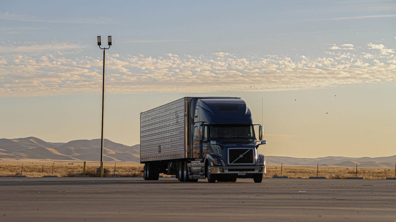 Heavy duty sleeper cab tractor and trailer parked at a truck stop at dusk